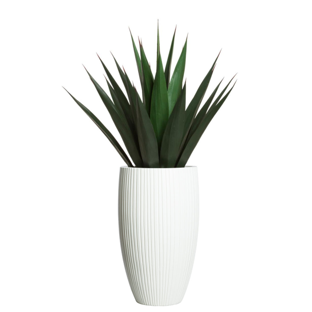 Artificial agave plant in tall white ribbed ceramic planter on white background