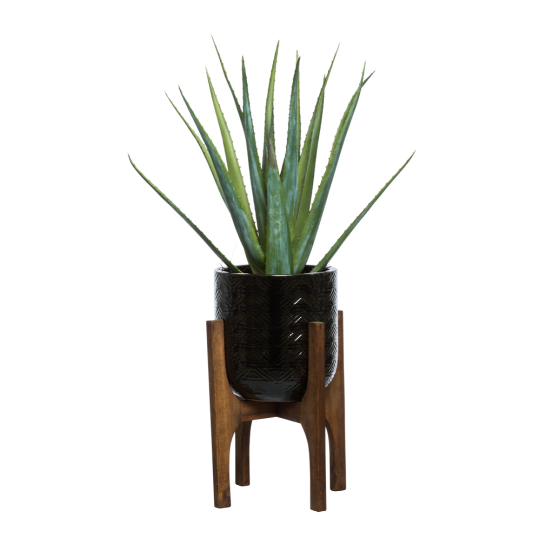 Artificial aloe plant in black textured pot on wooden mid-century modern stand