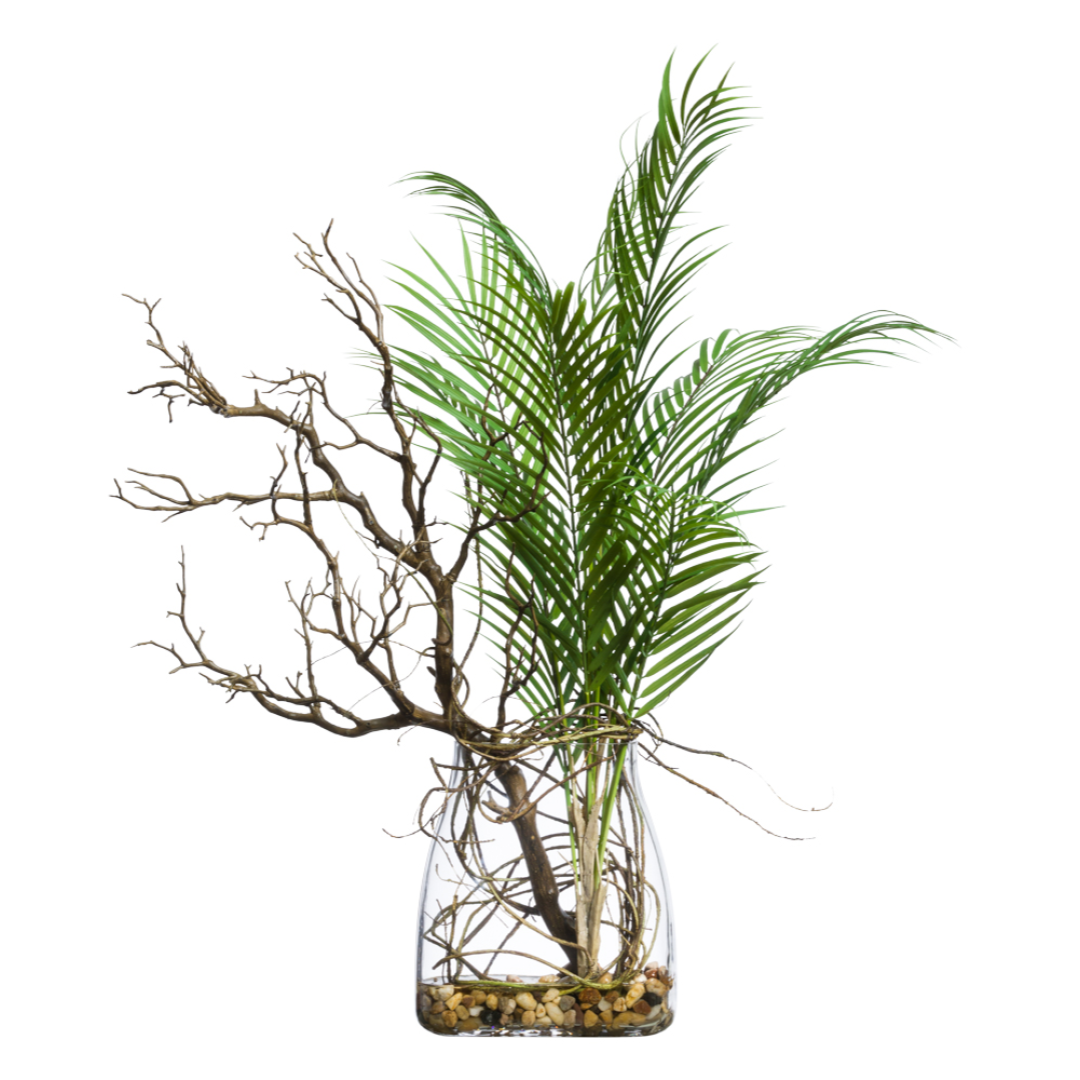 Artificial Areca palm with manzanita branches in glass vase with decorative pebbles