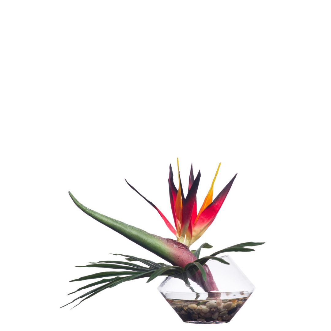 Artificial bird of paradise flower arrangement in clear glass vase with pebbles