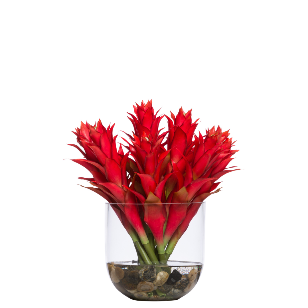 Artificial red bromeliad arrangement in clear glass vase with stones