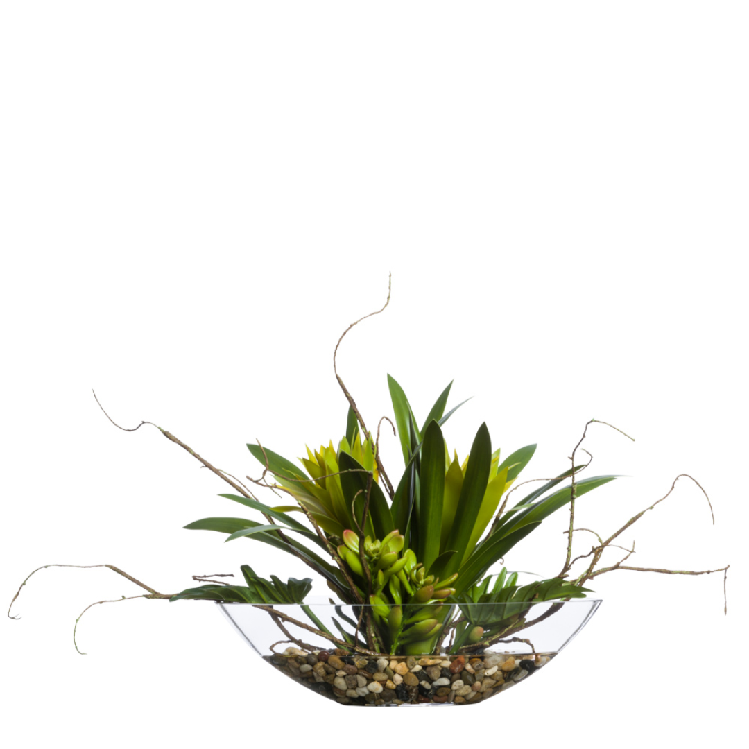 Artificial bromeliad and split leaf plant arrangement in clear glass bowl with decorative pebbles
