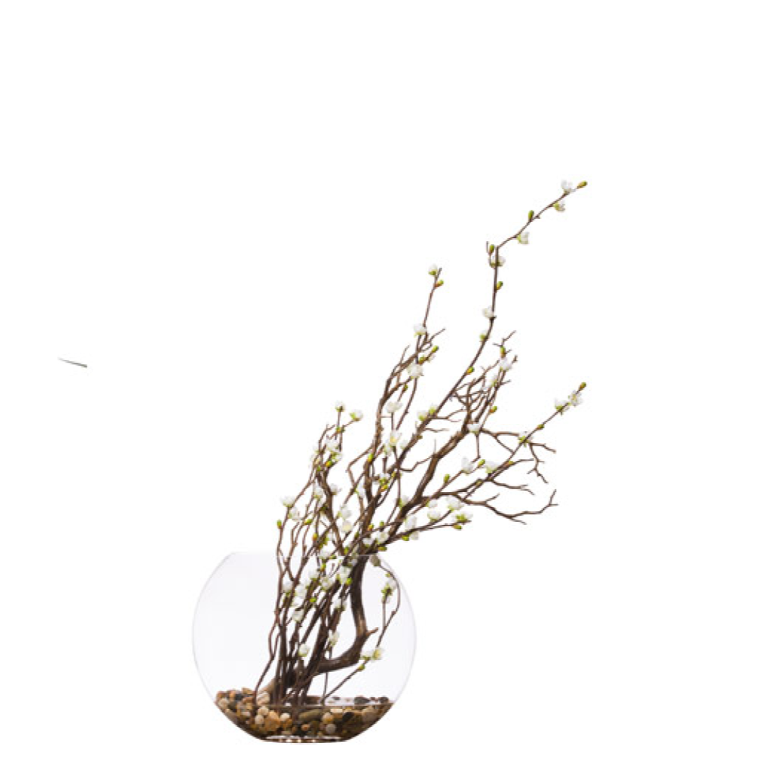 Artificial cherry blossom manzanita branches in a round glass vase with pebbles