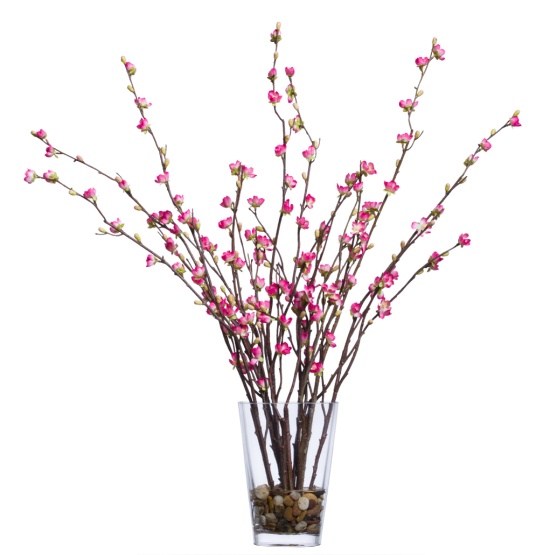 Artificial cherry blossom branches with pink flowers in a clear glass vase with pebbles