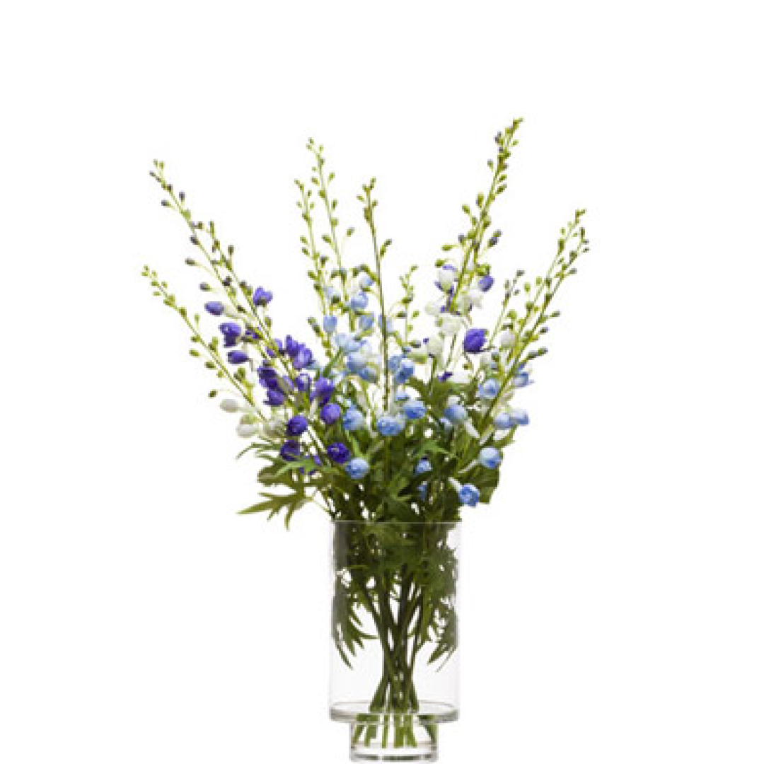 Artificial blue and white delphinium flower arrangement in clear glass vase
