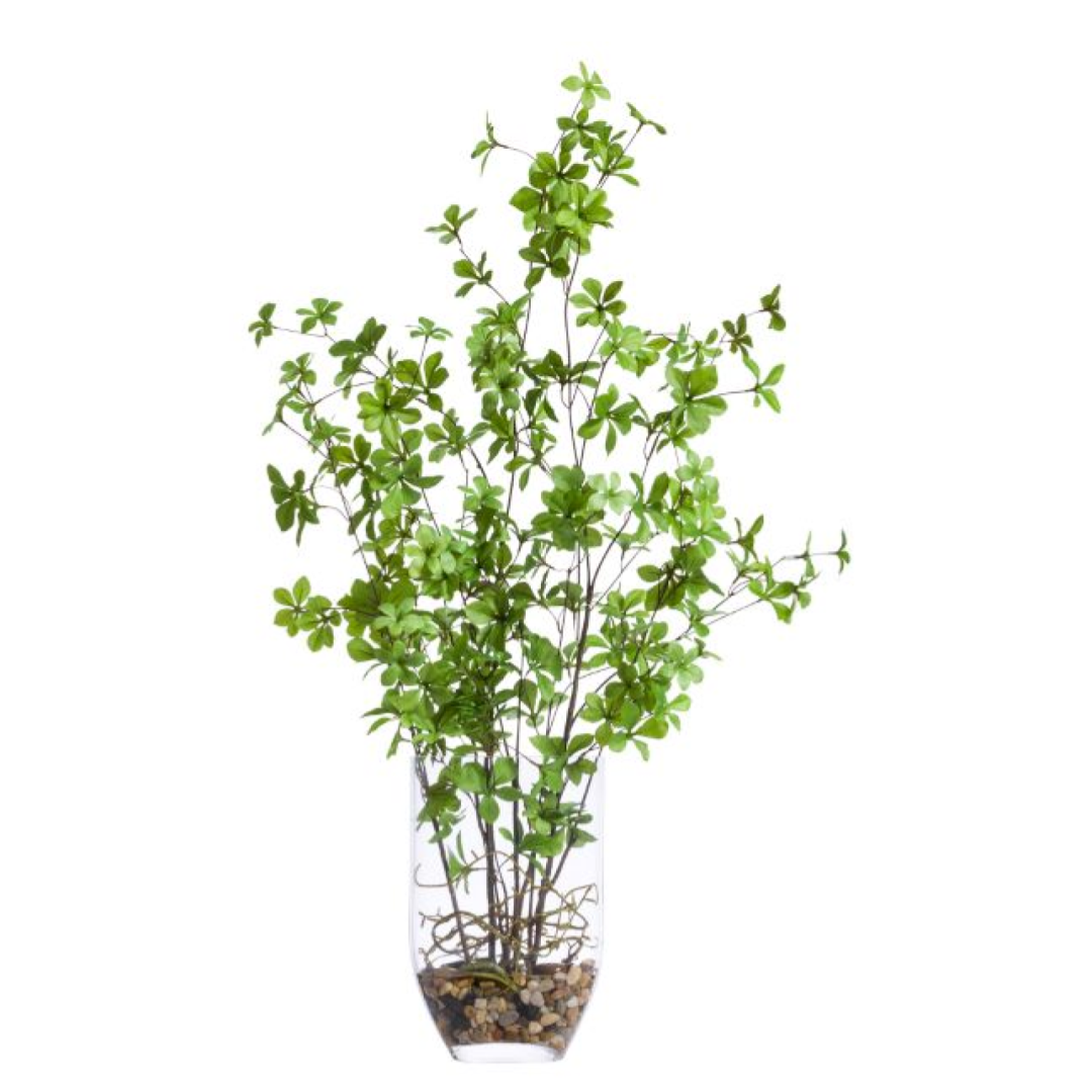 Realistic artificial green leafy plant in a clear glass vase with pebbles, white background