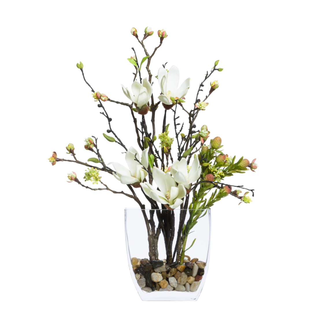 Artificial magnolia bud branch arrangement in glass vase with pebbles, lifelike floral decor