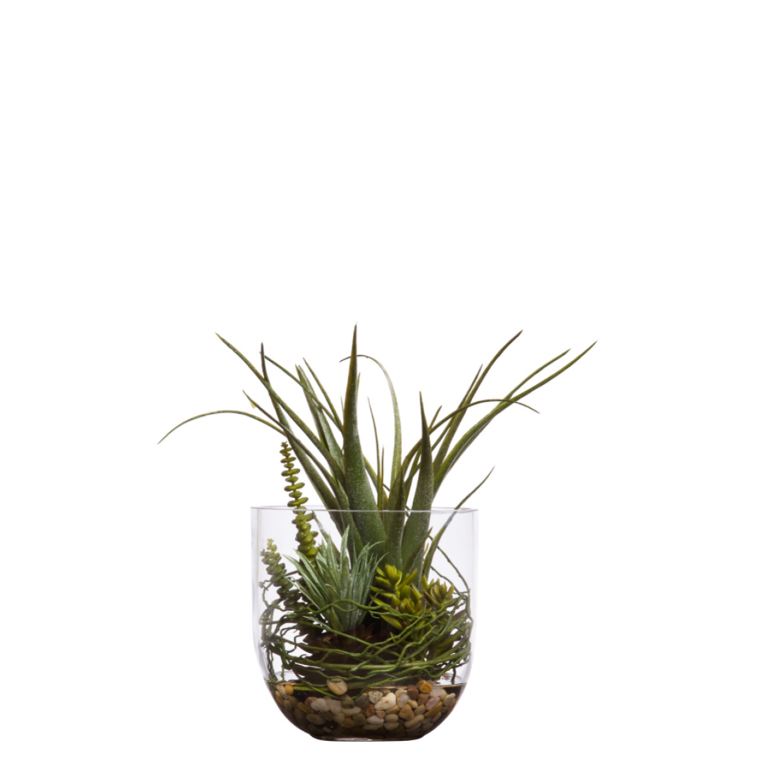 Artificial succulents arrangement in glass vase with pebbles and greenery on white background