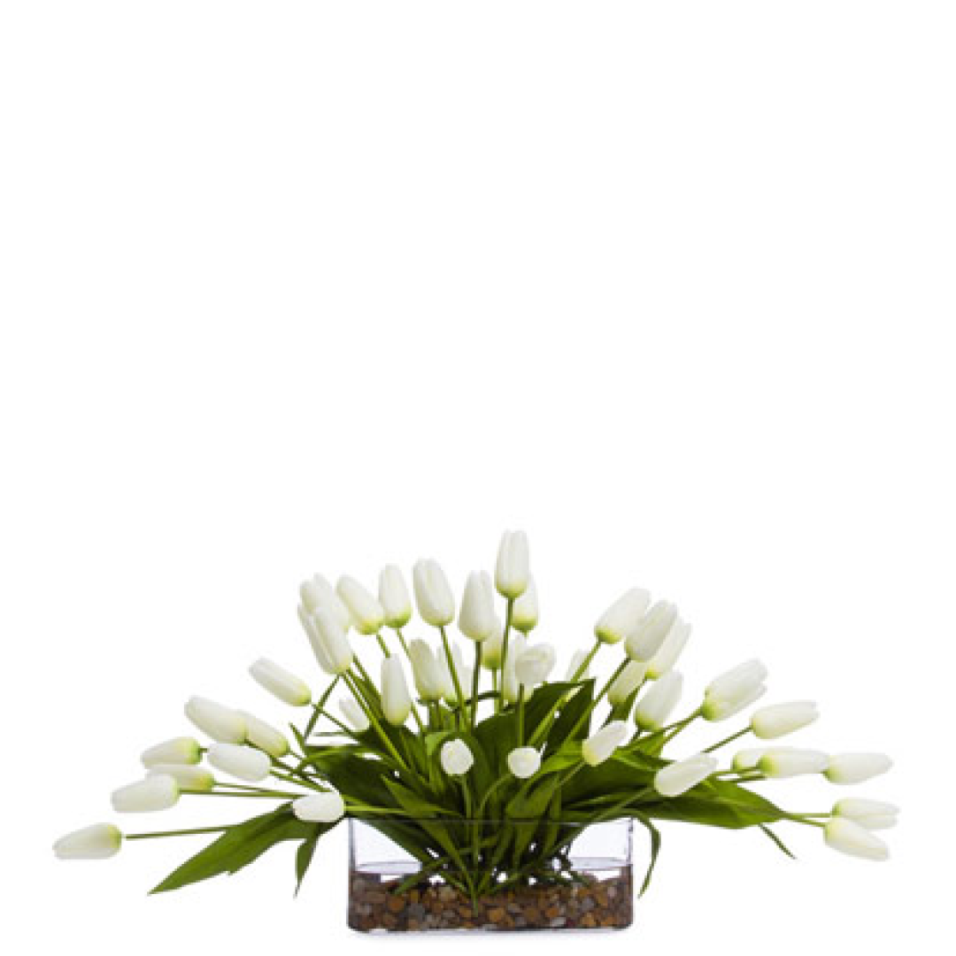 Artificial white tulip arrangement in a rectangular glass vase with green leaves