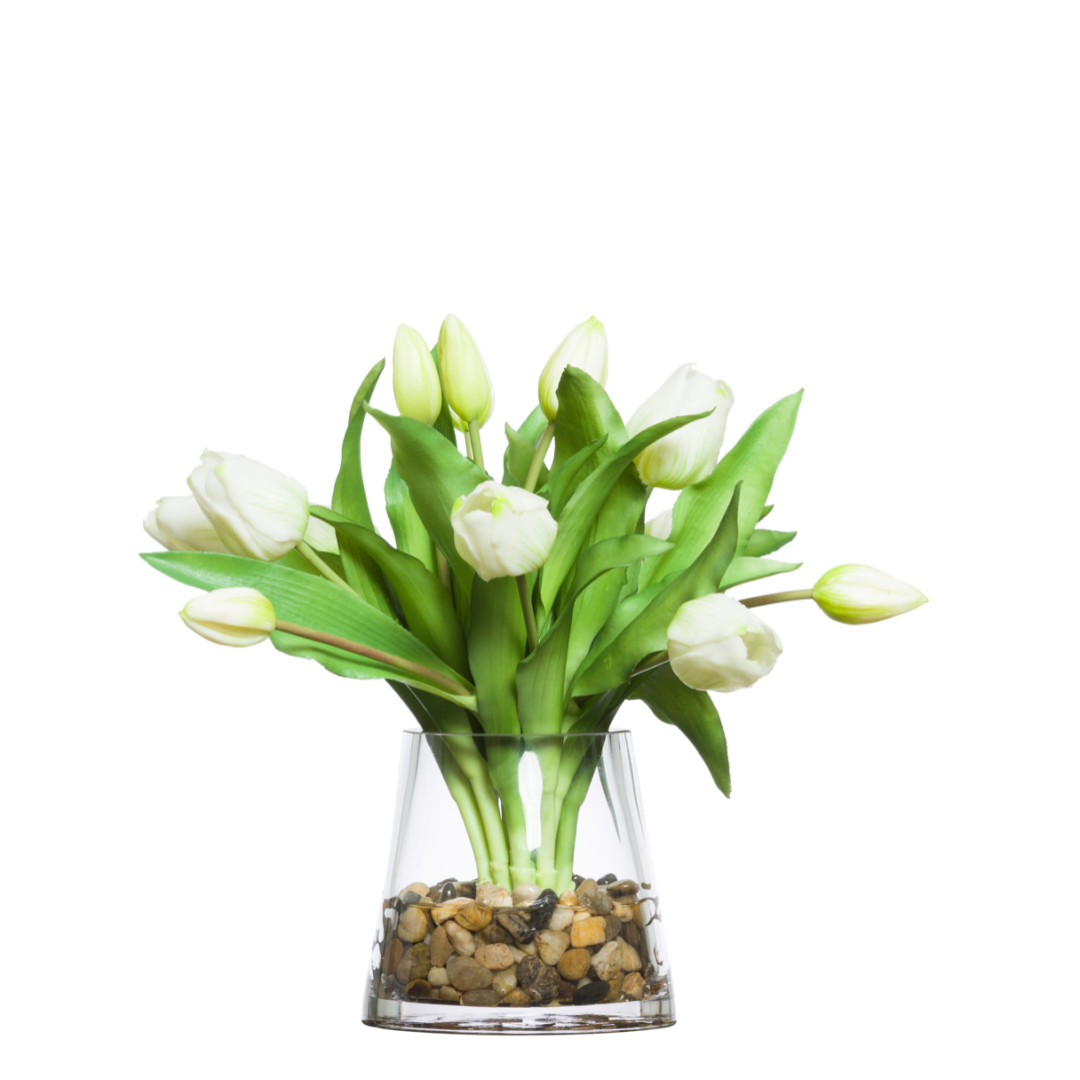 White artificial tulip arrangement in clear glass vase with pebbles, realistic greenery