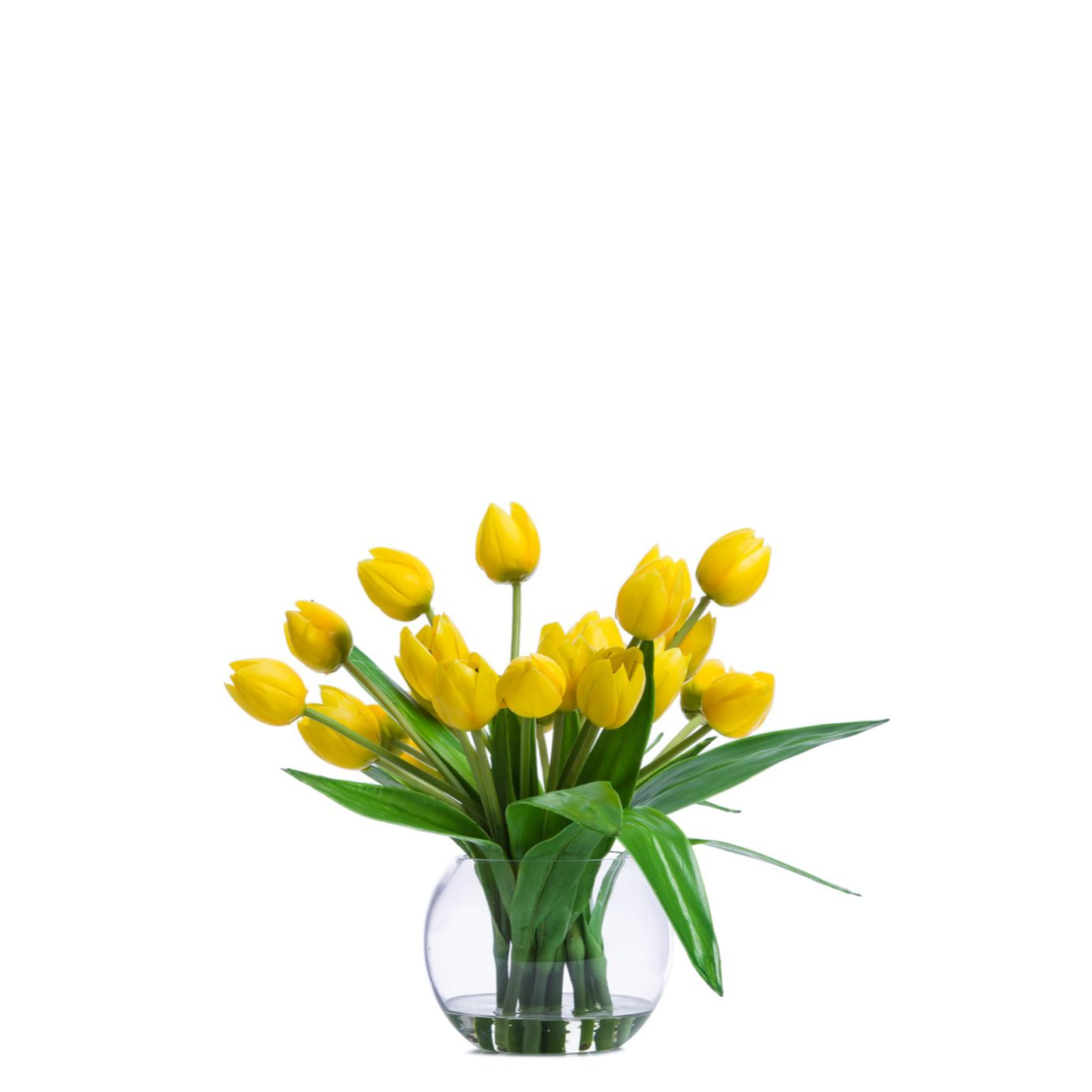 Artificial yellow tulip bouquet in clear glass vase with realistic green leaves