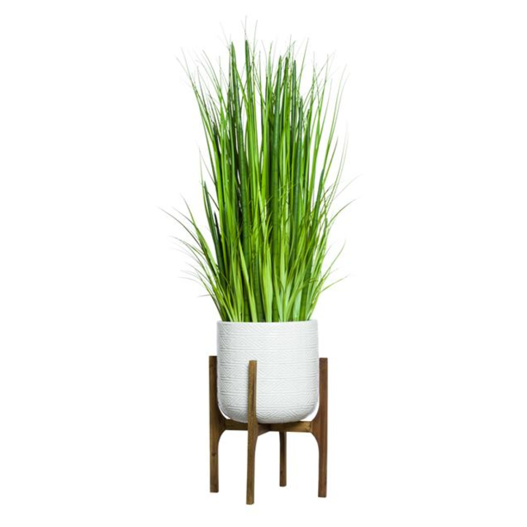 Artificial grass mix and snake plant in white textured pot on wooden stand