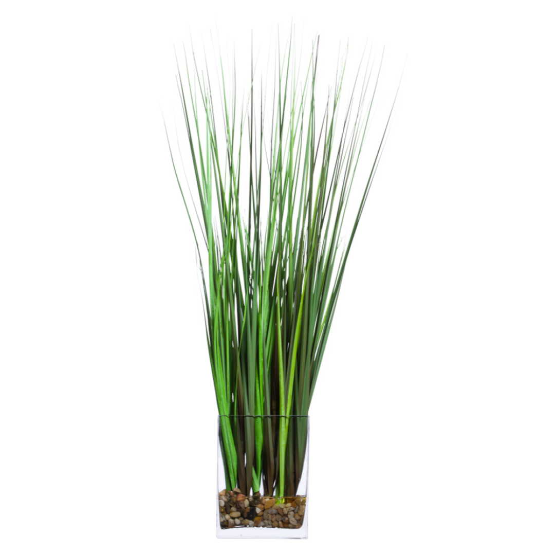 Artificial grass onion plant in clear glass vase with decorative stones