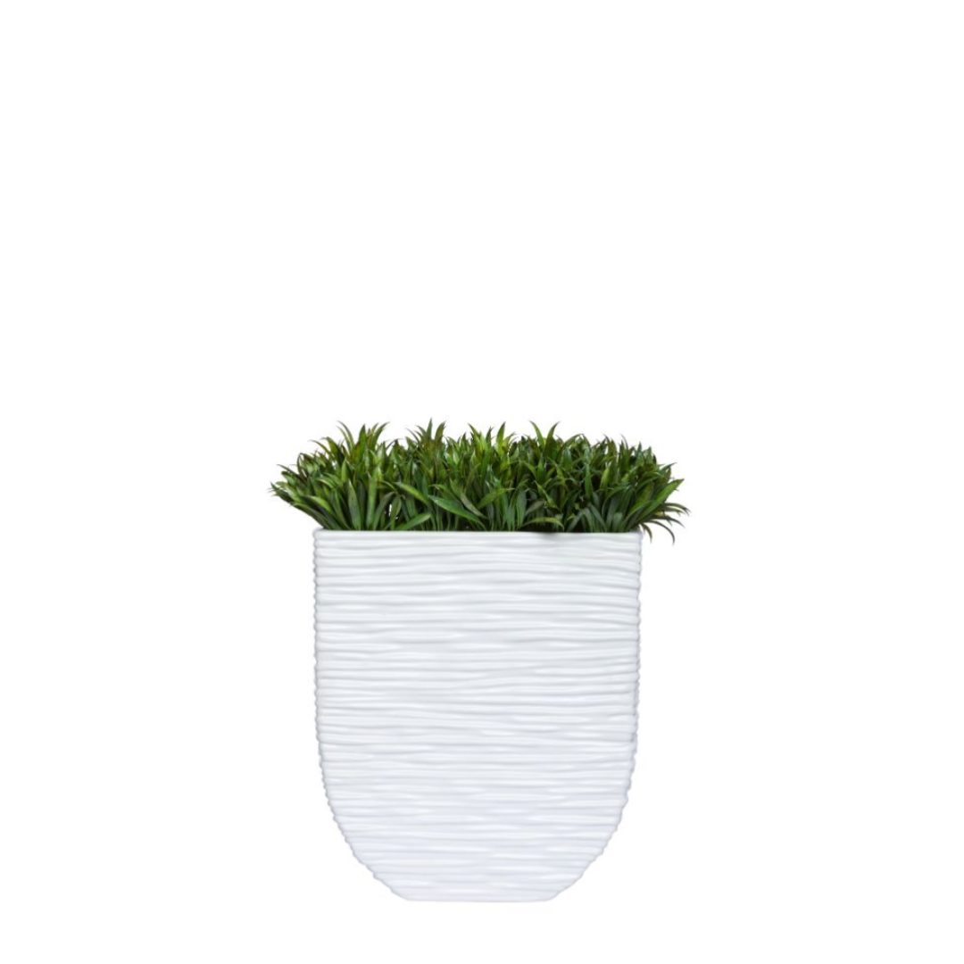 Artificial grass plant in textured white ceramic planter on white background
