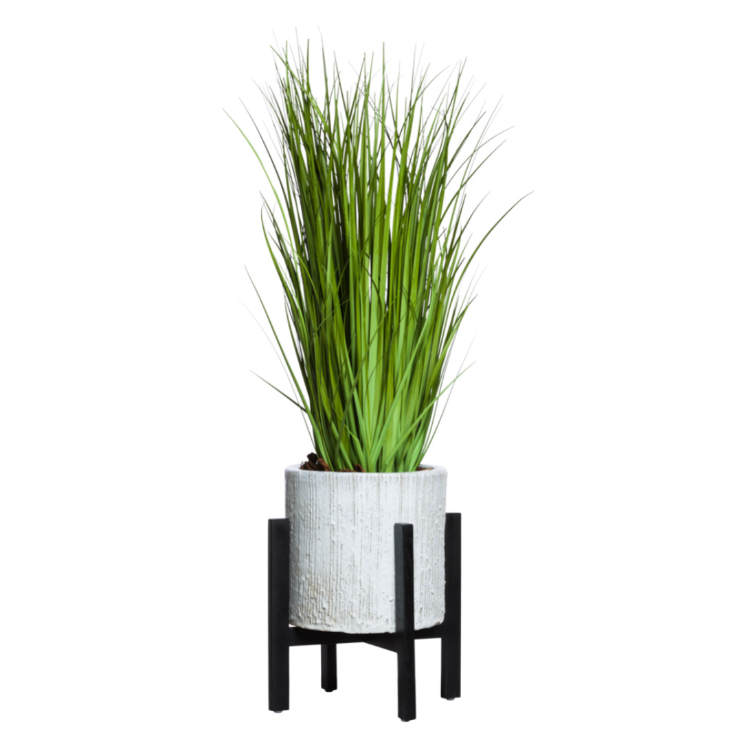 Artificial green grass plant in textured white pot with black metal stand