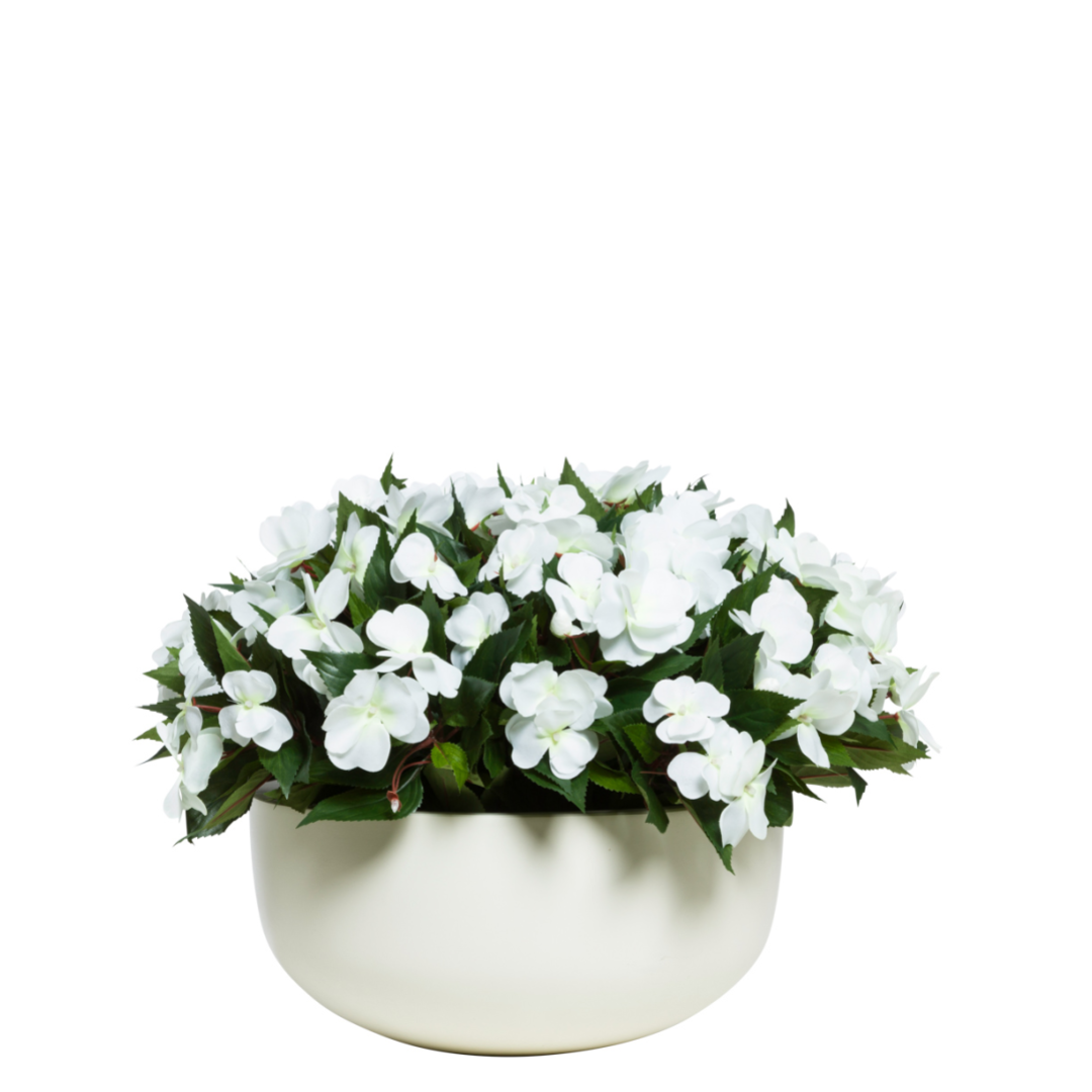 artificial white impatiens flowers in a round, modern white ceramic pot