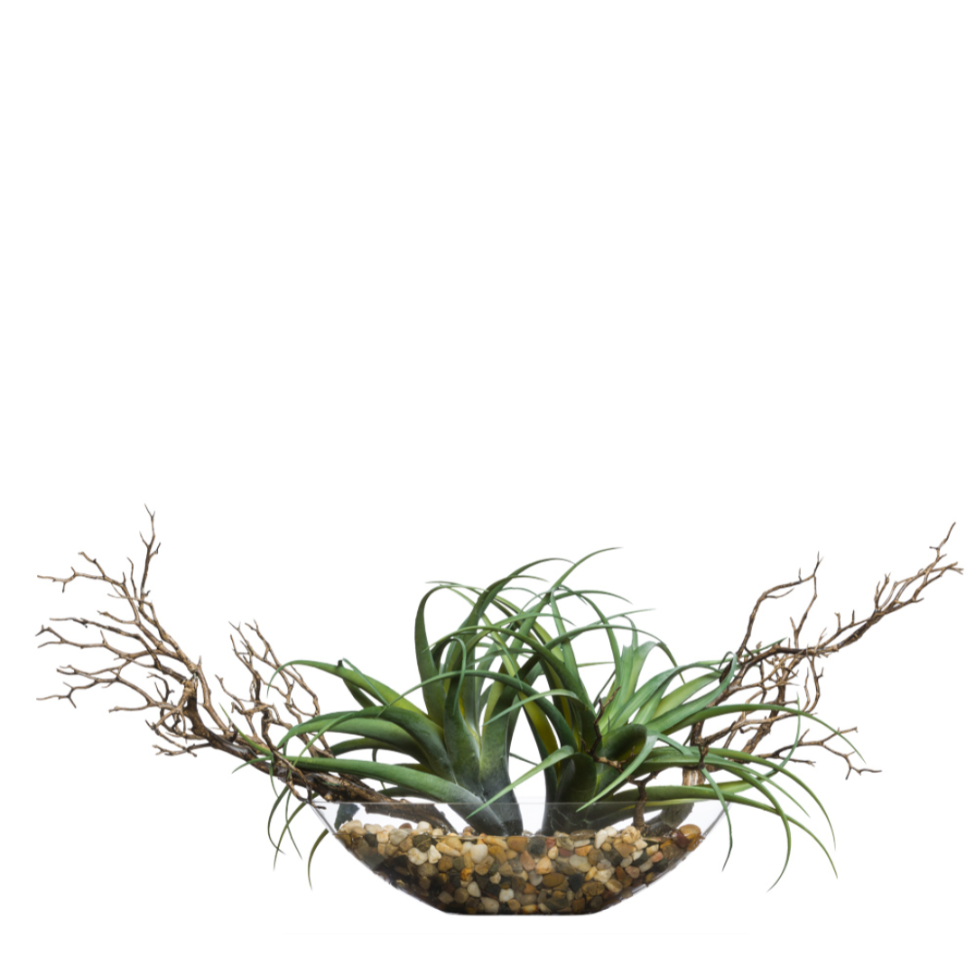 Artificial succulent arrangement in clear glass bowl with pebbles and decorative branches