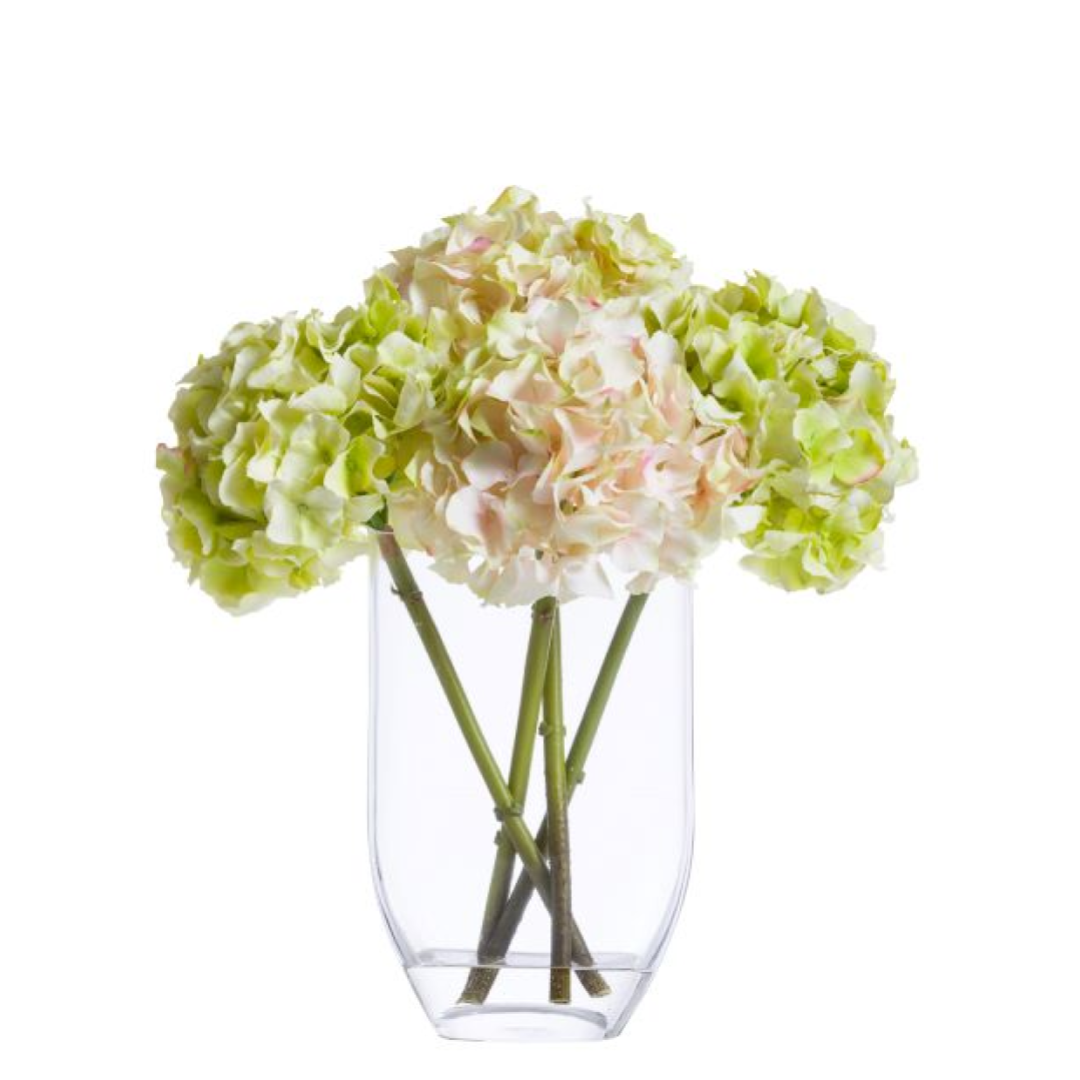 Artificial hydrangea bouquet with pale green and blush petals in a clear glass vase