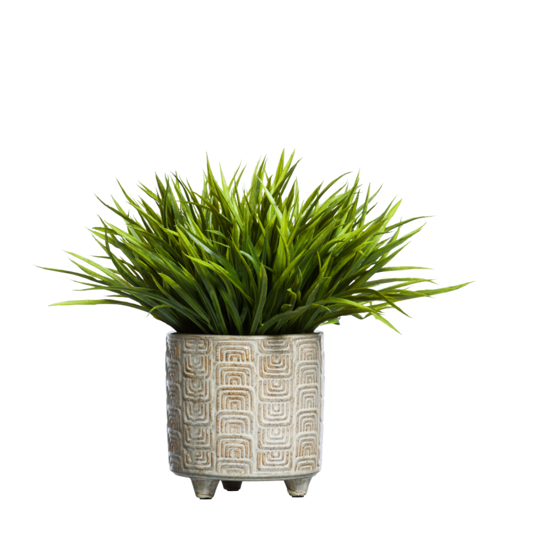 Artificial grass plant in textured ceramic pot on white background