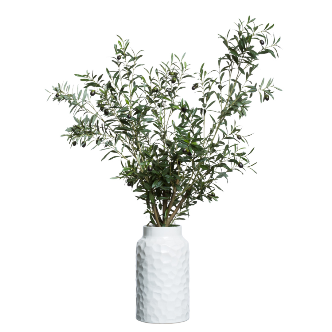 Artificial olive tree arrangement in textured white vase on white background