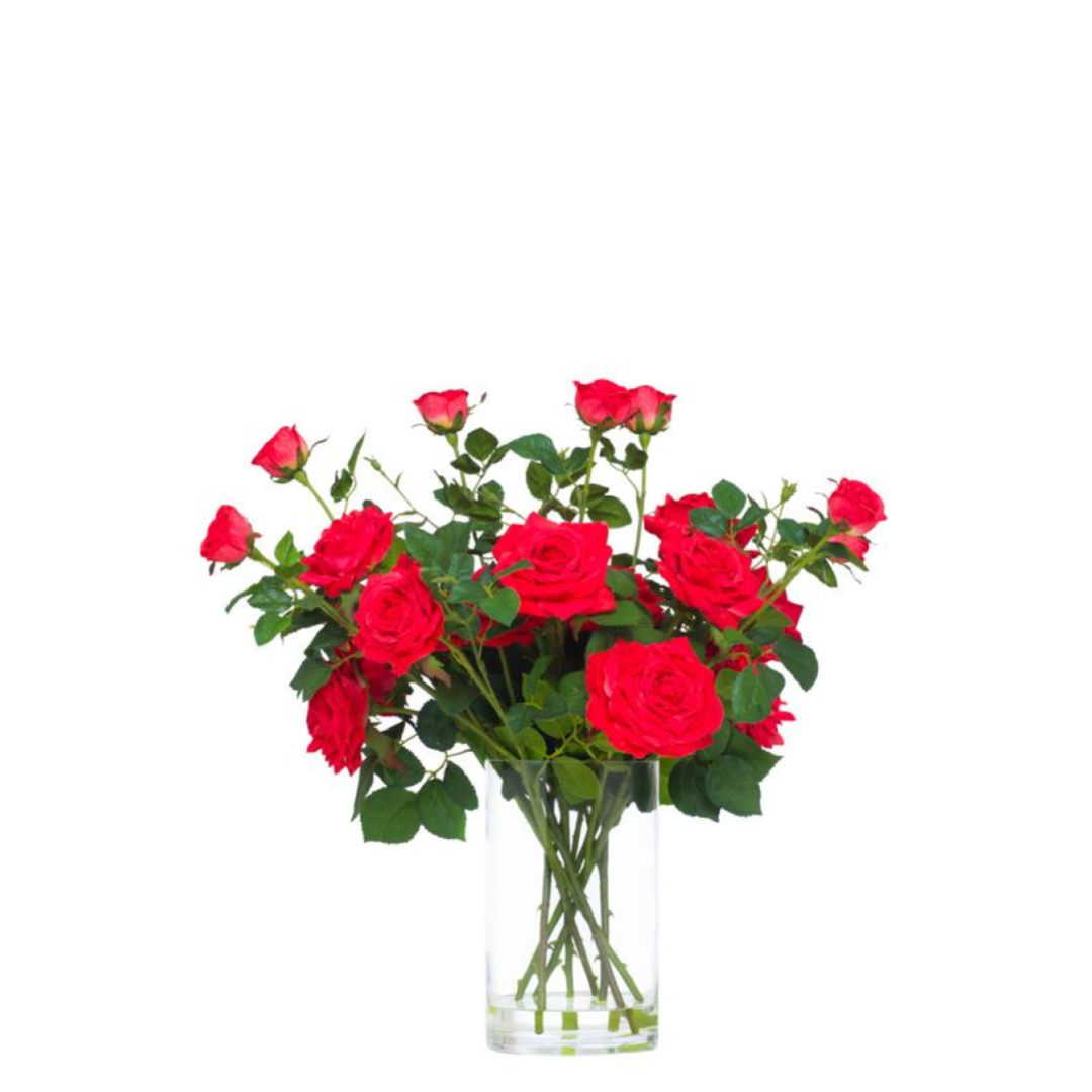 Bouquet of realistic red roses with green leaves in a clear glass vase on white background