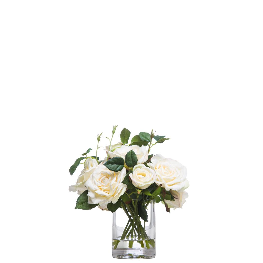 White artificial rose bouquet in a clear glass vase with green leaves