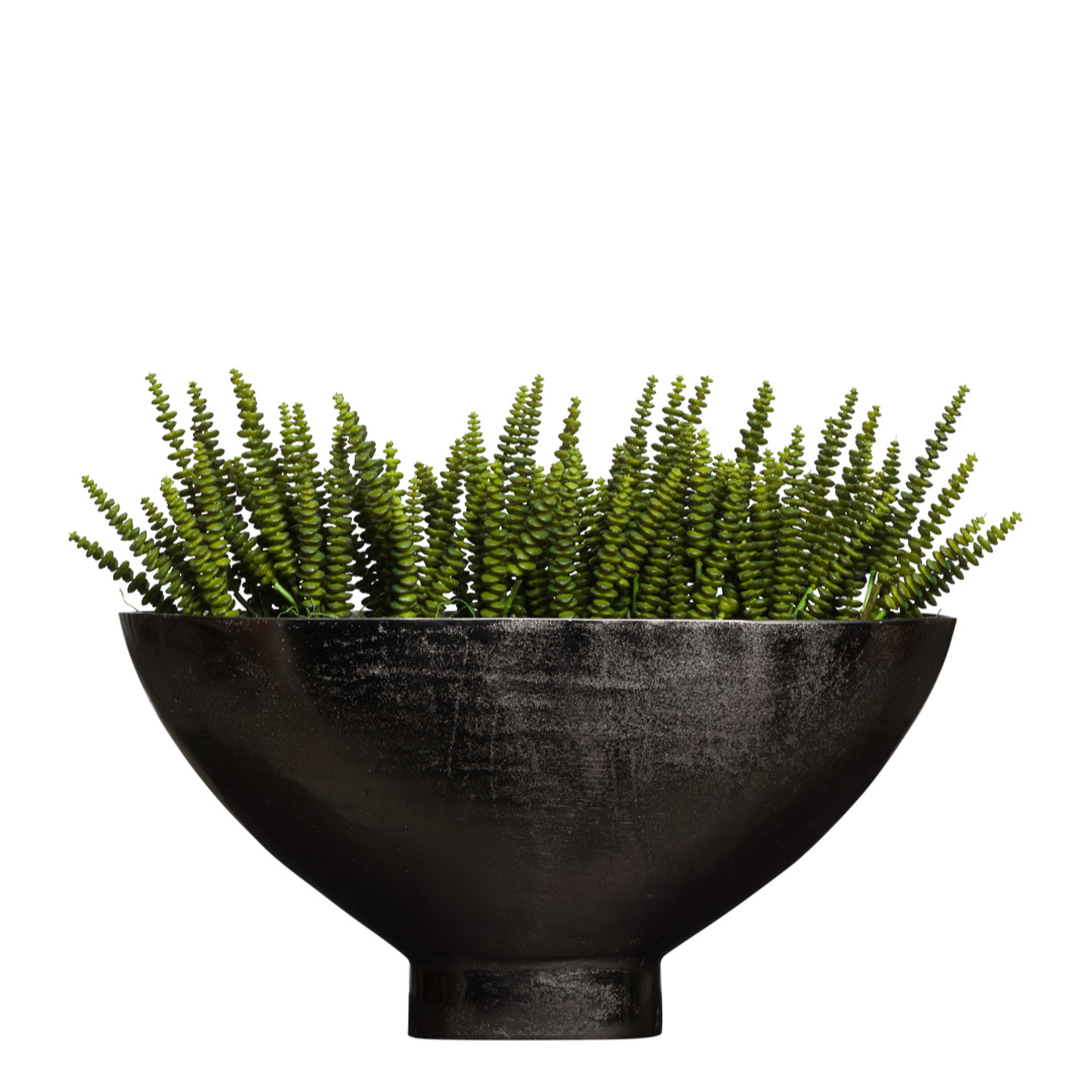 Artificial succulent arrangement in a black round planter on white background