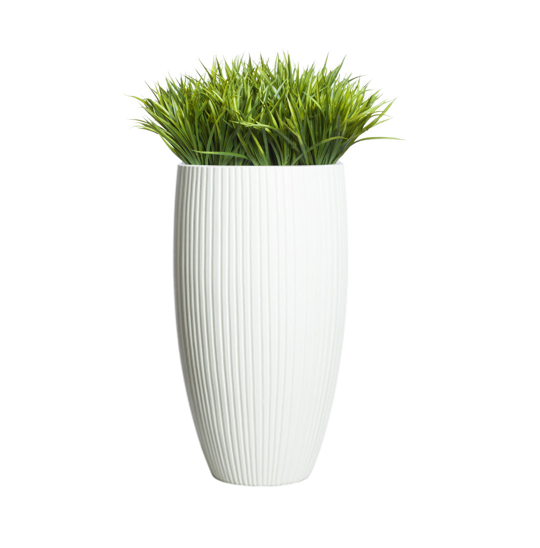 Artificial sword grass in a tall ribbed white planter on white background