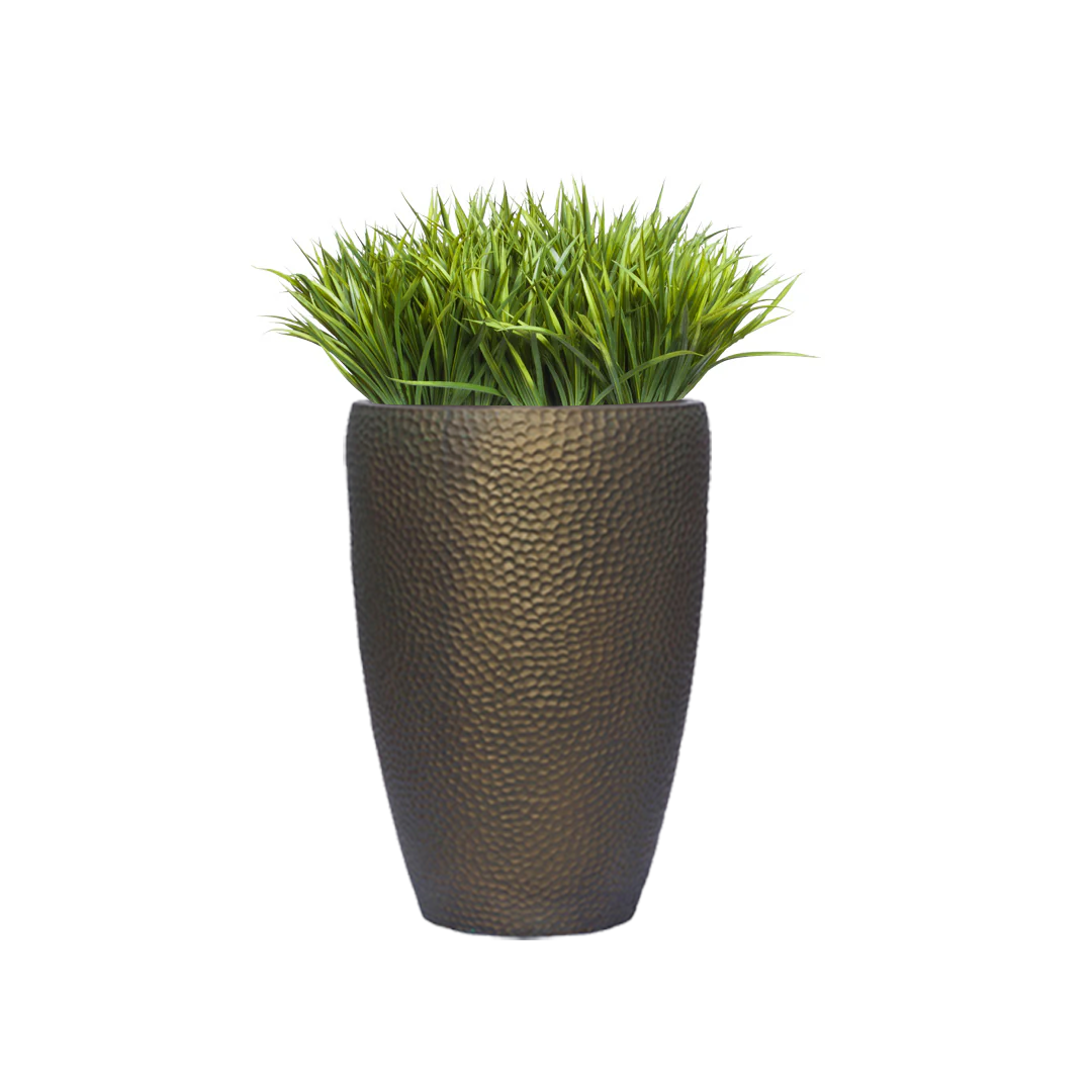 Artificial sword grass in textured bronze planter against white background