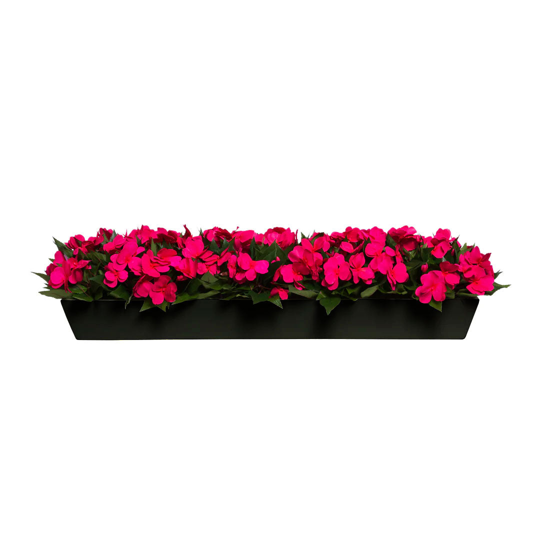 Bright pink artificial impatiens flowers in a rectangular black planter, realistic foliage
