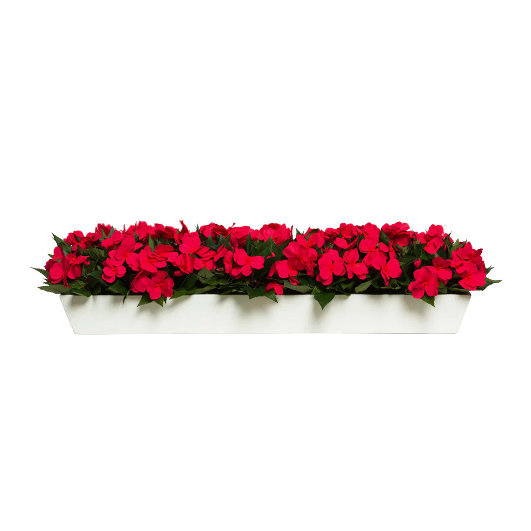 Artificial red impatiens flowers in a white rectangular planter, realistic foliage