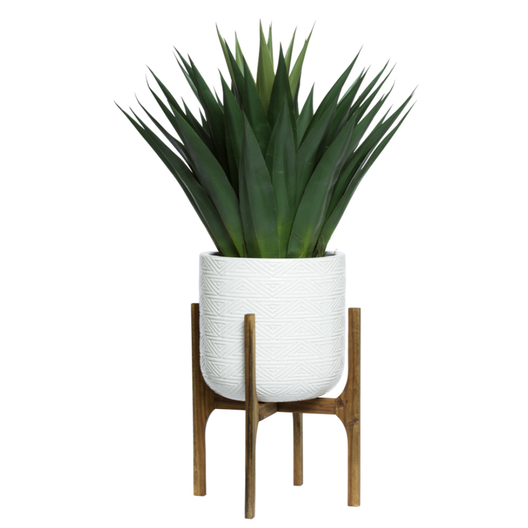 Artificial agave plant in textured white geometric pot on wooden stand
