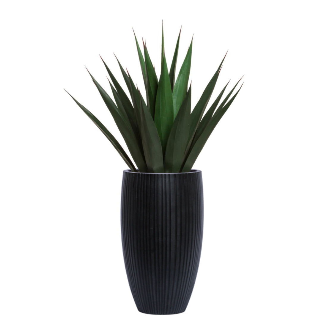Artificial agave plant in tall black ribbed planter on white background
