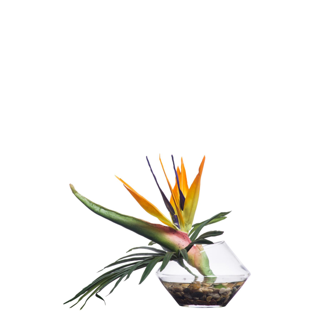 Bird of Paradise artificial flower in clear glass vase with pebbles on white background