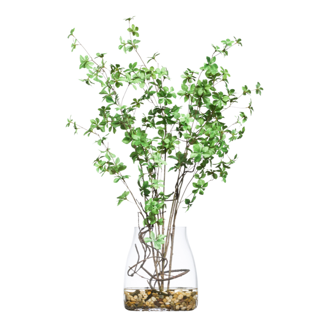 Artificial green foliage arrangement in clear glass vase with decorative stones