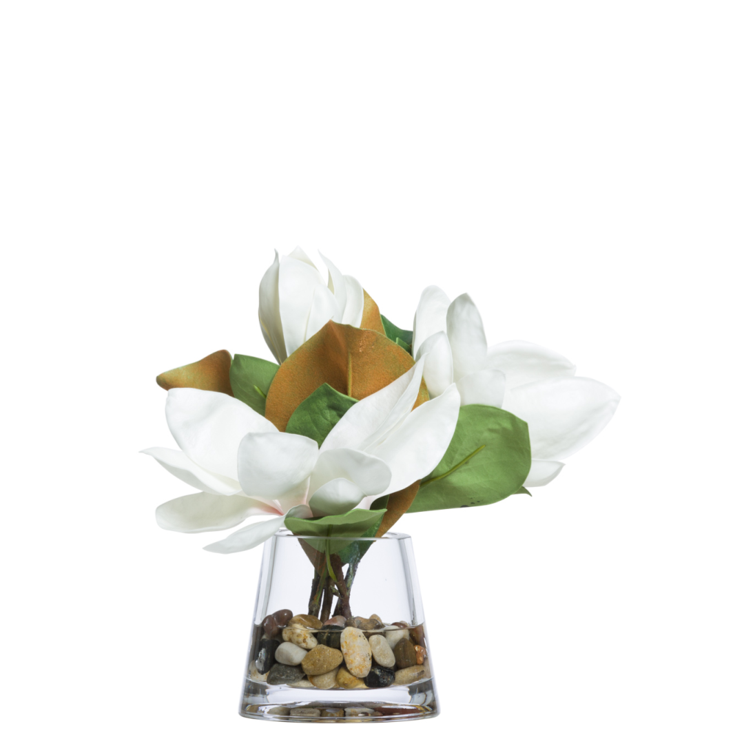 Artificial white magnolia flowers in glass vase with pebbles, modern floral decor