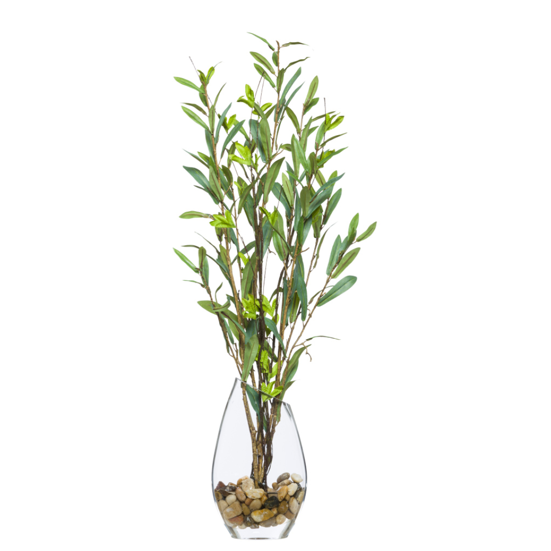 Artificial greenery stems in clear glass vase with decorative stones, botanical decor accent