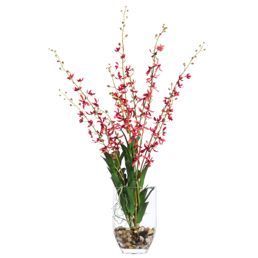 Artificial red vanda orchids in tall glass vase with green leaves and decorative pebbles