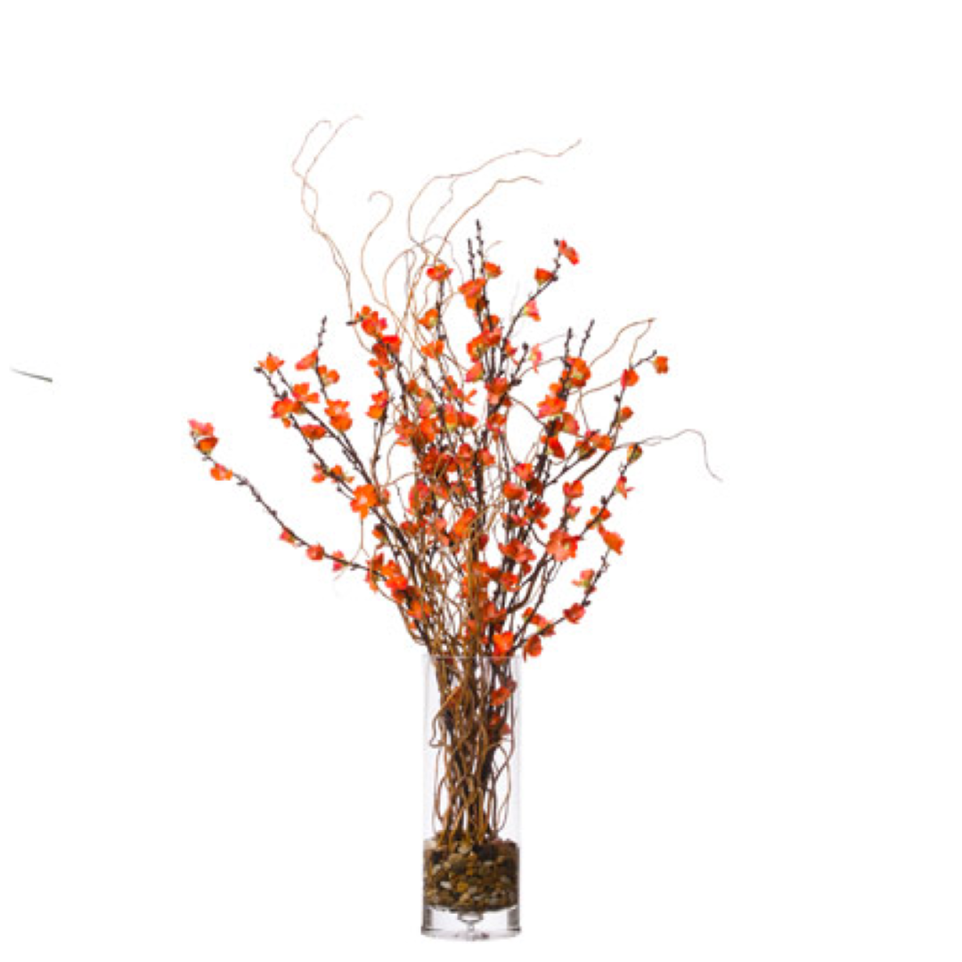 Artificial plum blossom branches with orange flowers in tall glass vase