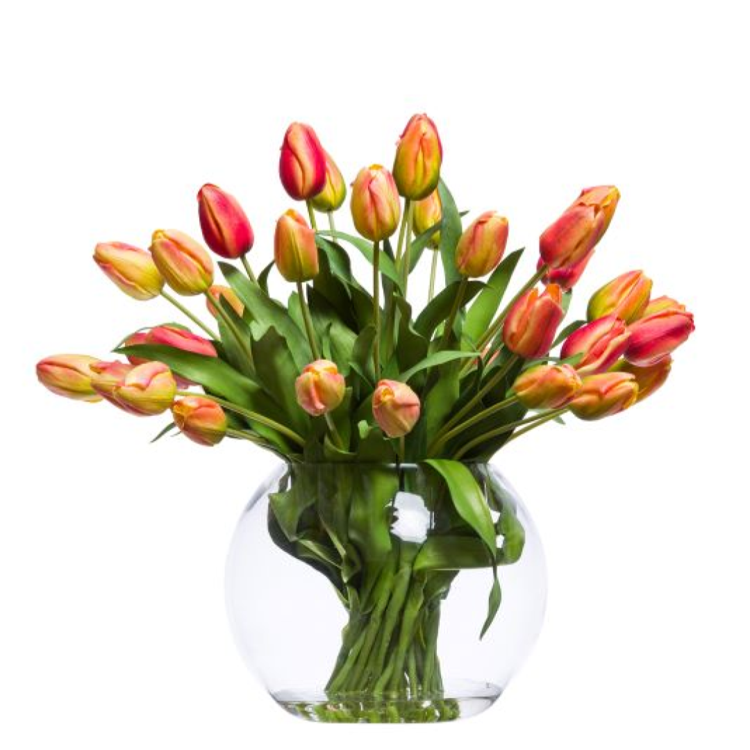 Realistic artificial orange and yellow tulips in a clear round glass vase