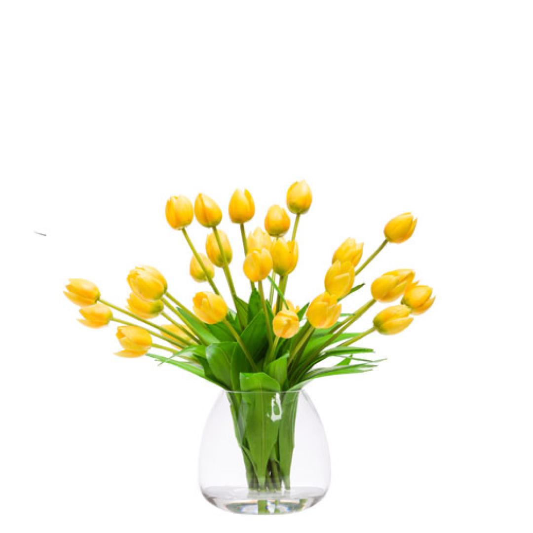 Yellow artificial tulip arrangement in a clear glass vase with green leaves