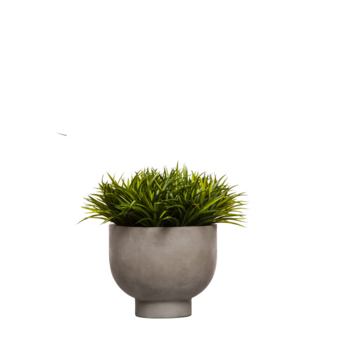 Artificial grass plant in a modern gray round planter on white background