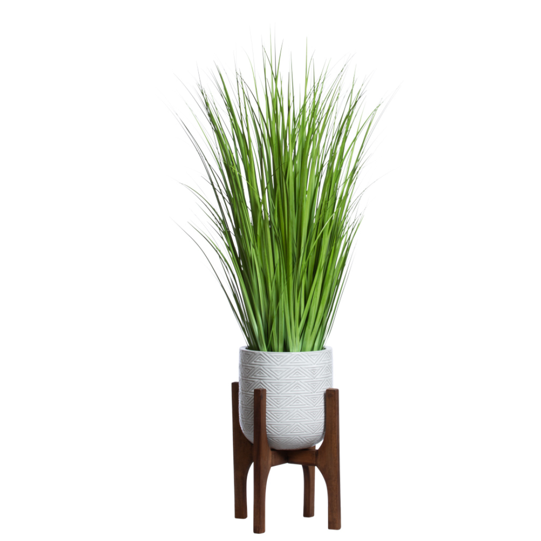 Artificial grass plant in textured white pot with wooden stand, modern home decor