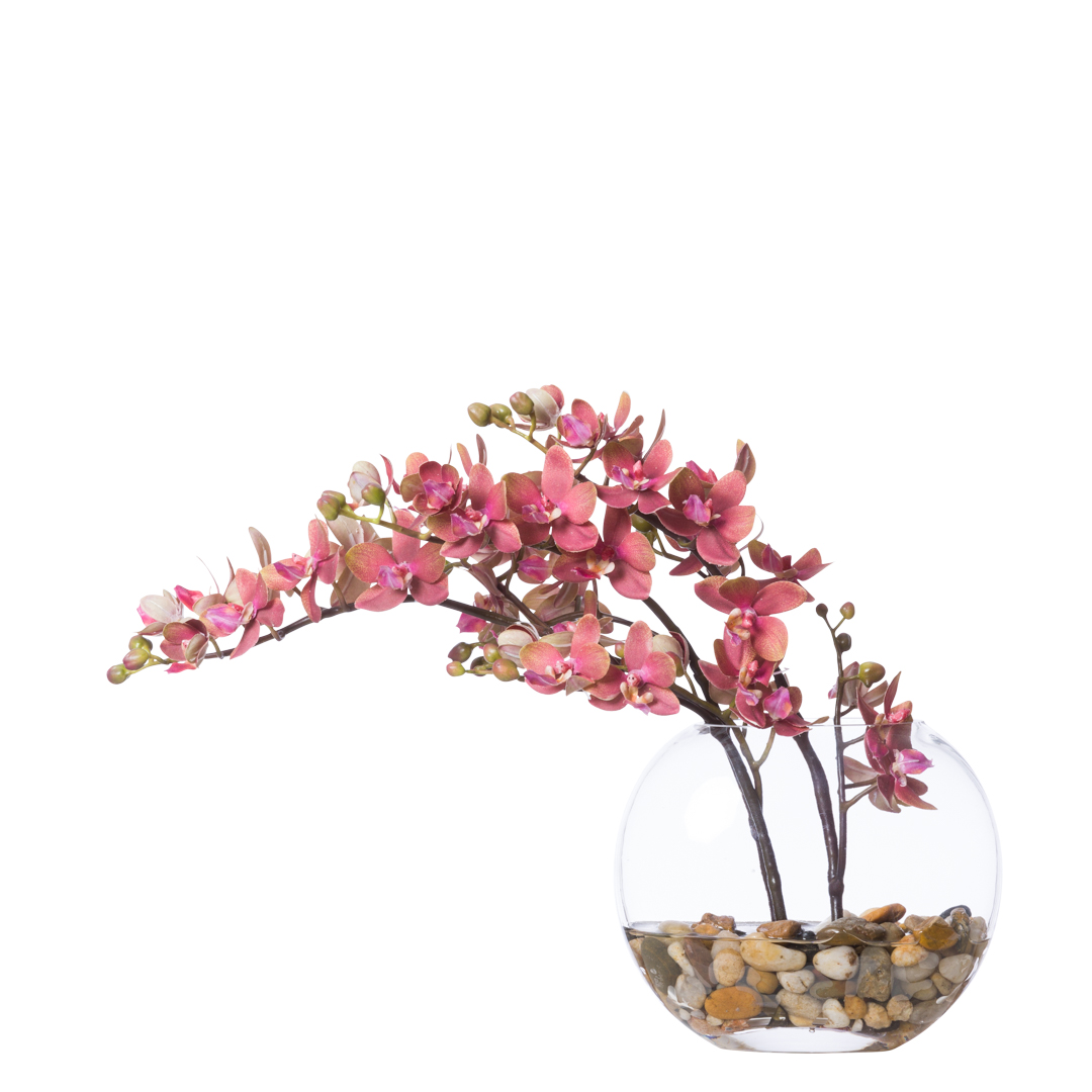 Pink artificial orchid arrangement in round glass vase with decorative stones