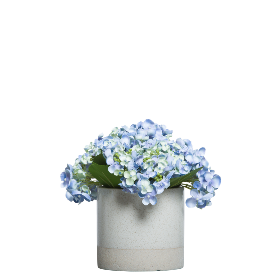 Artificial blue hydrangea arrangement in a modern ceramic pot on white background