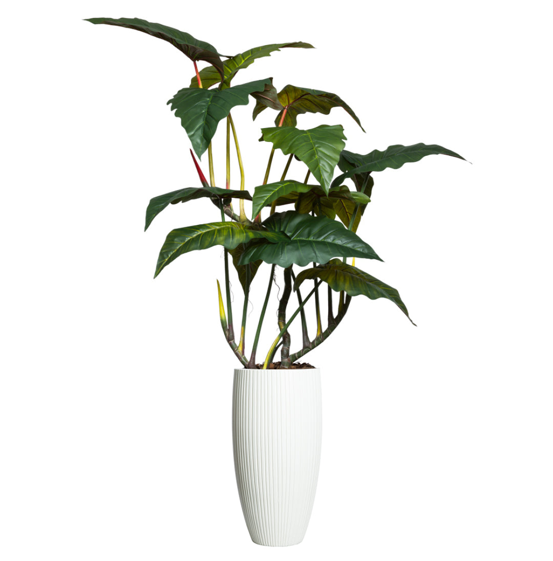 Artificial giant philodendron plant with large green leaves in a tall ribbed white planter