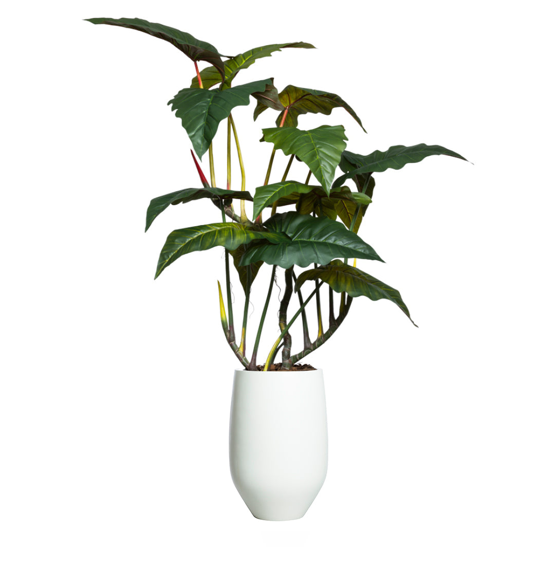 Artificial philodendron plant with large green leaves in a tall white pot on white background