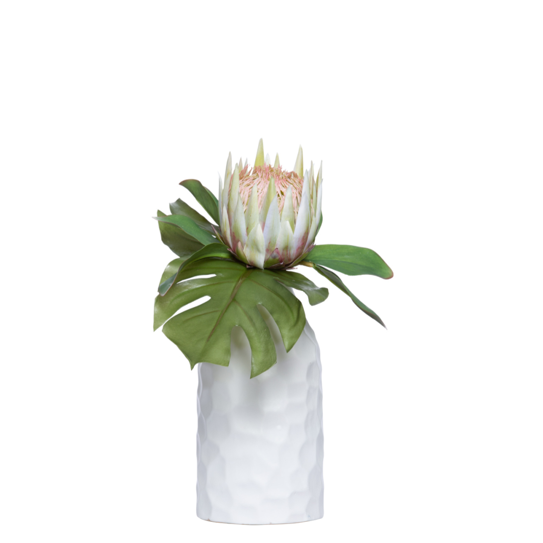 Artificial protea flower with split leaf in white textured vase on white background