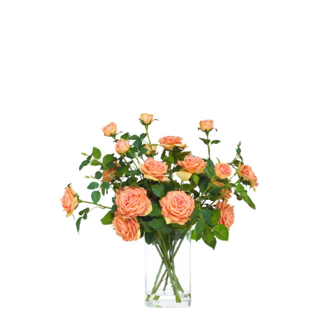 Realistic artificial orange roses arrangement in a clear glass vase on white background