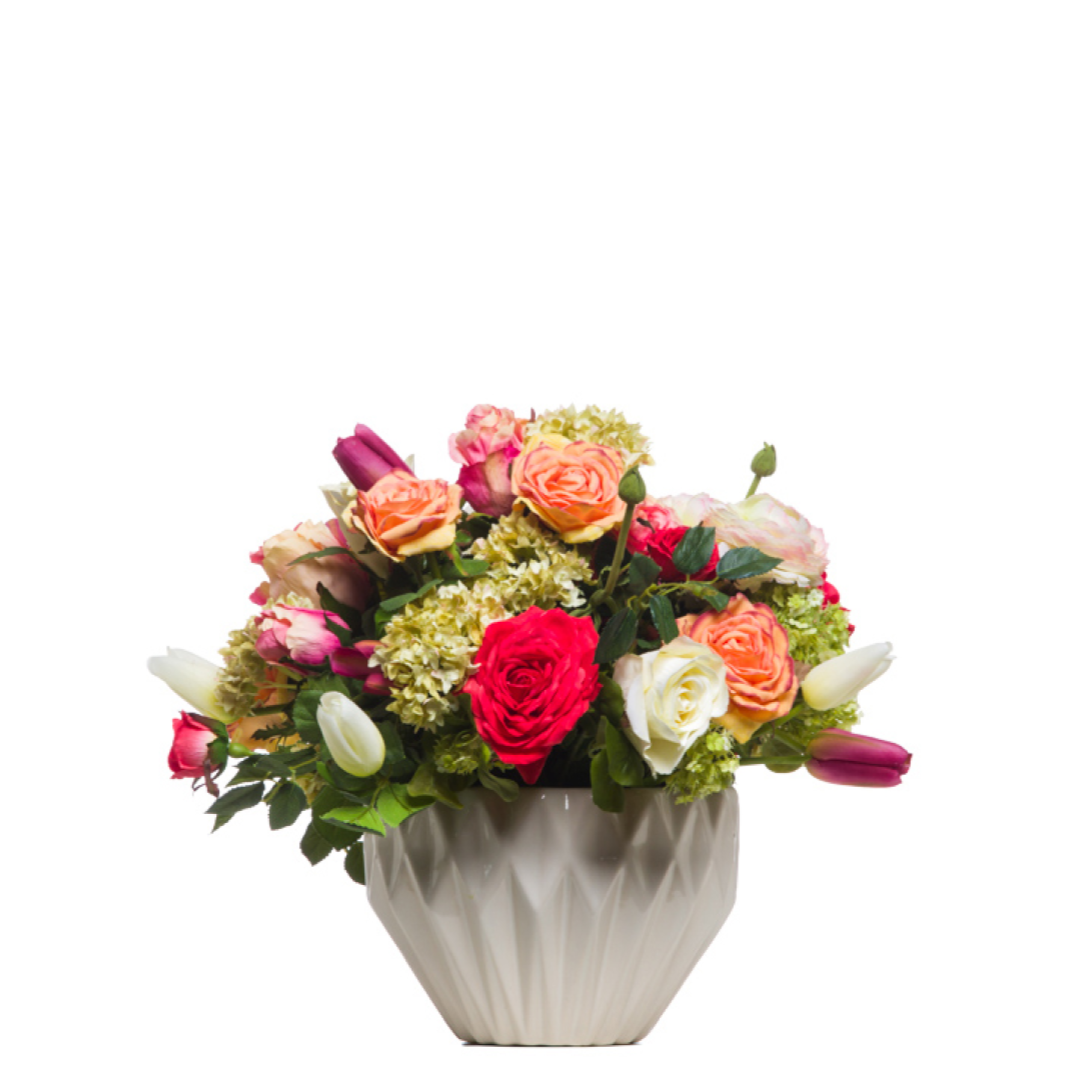 Mixed artificial roses, tulips, and greenery in a modern white ceramic vase arrangement.